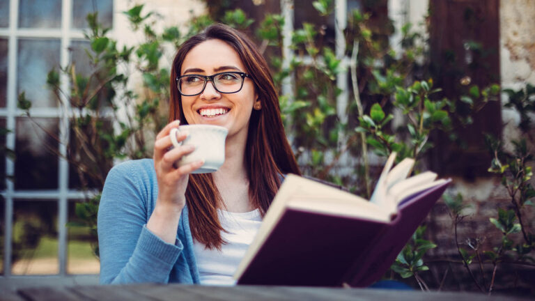 Woman drinking tea and reading a book on her veranda for her spring activity